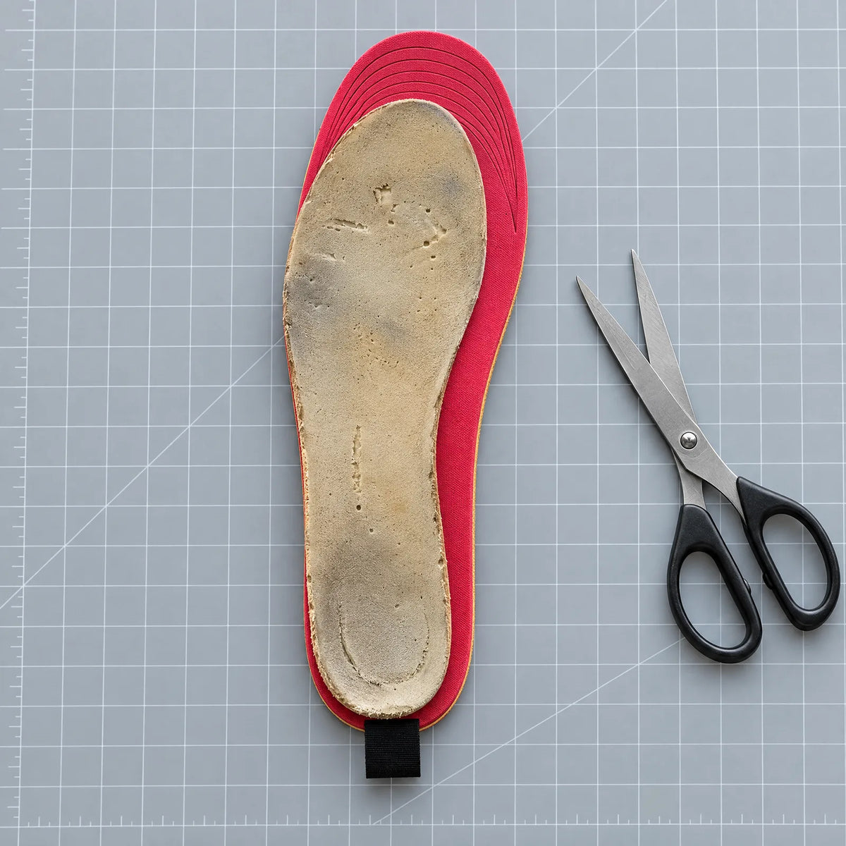 Heated insole with an old insole as a template and scissors for trimming
