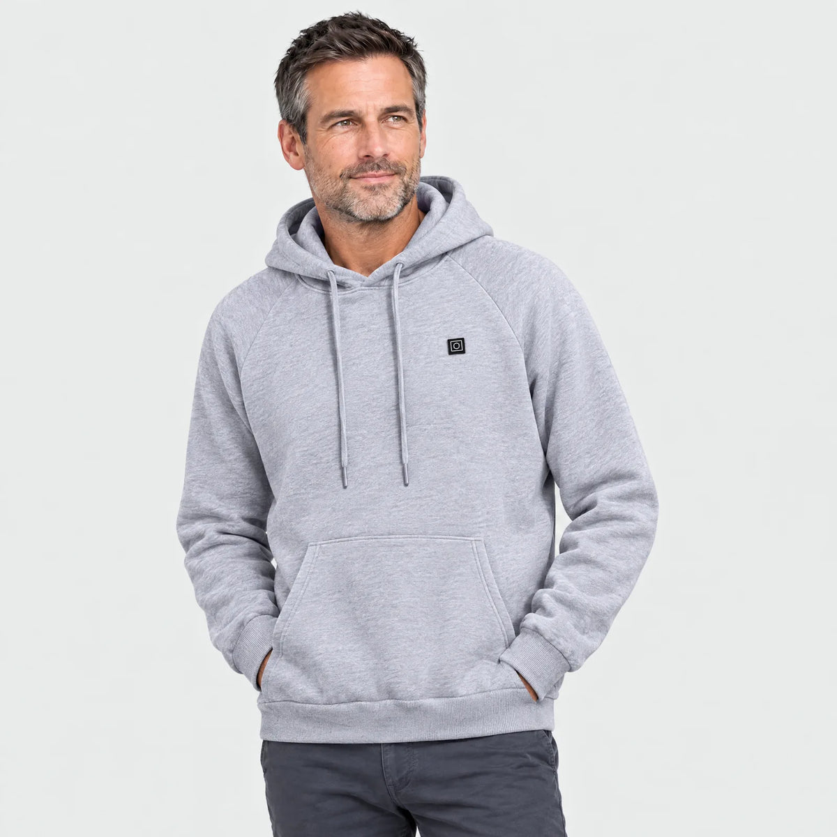 Man wearing the gray heated hoodie, heat-level button on the chest