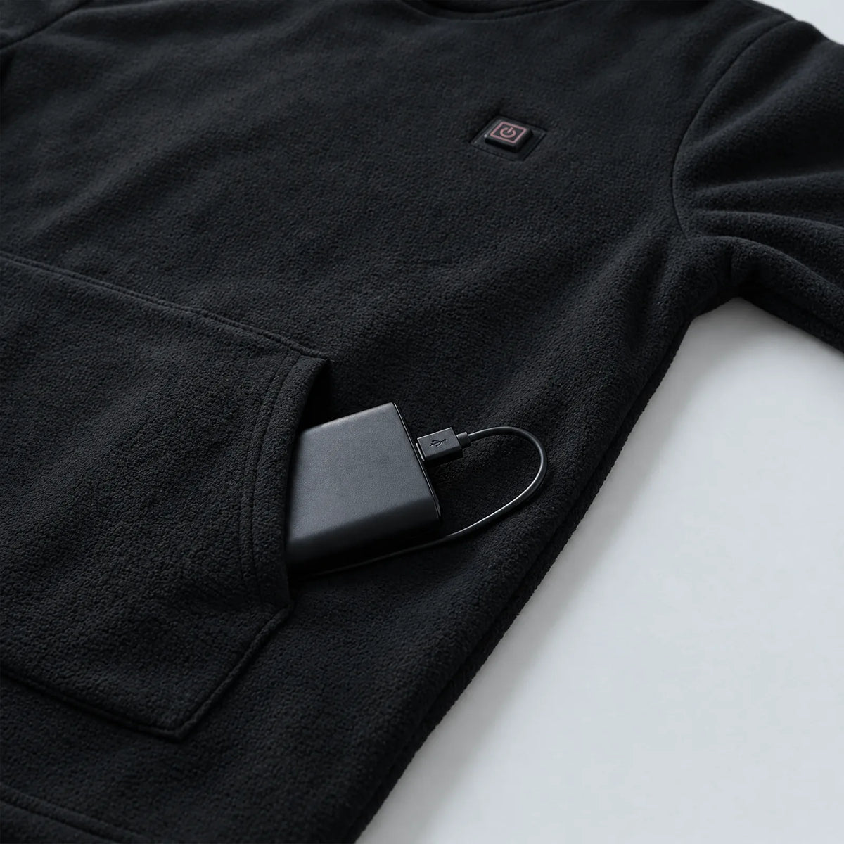 Power bank in the kangaroo pocket of the black heated hoodie, button on the chest