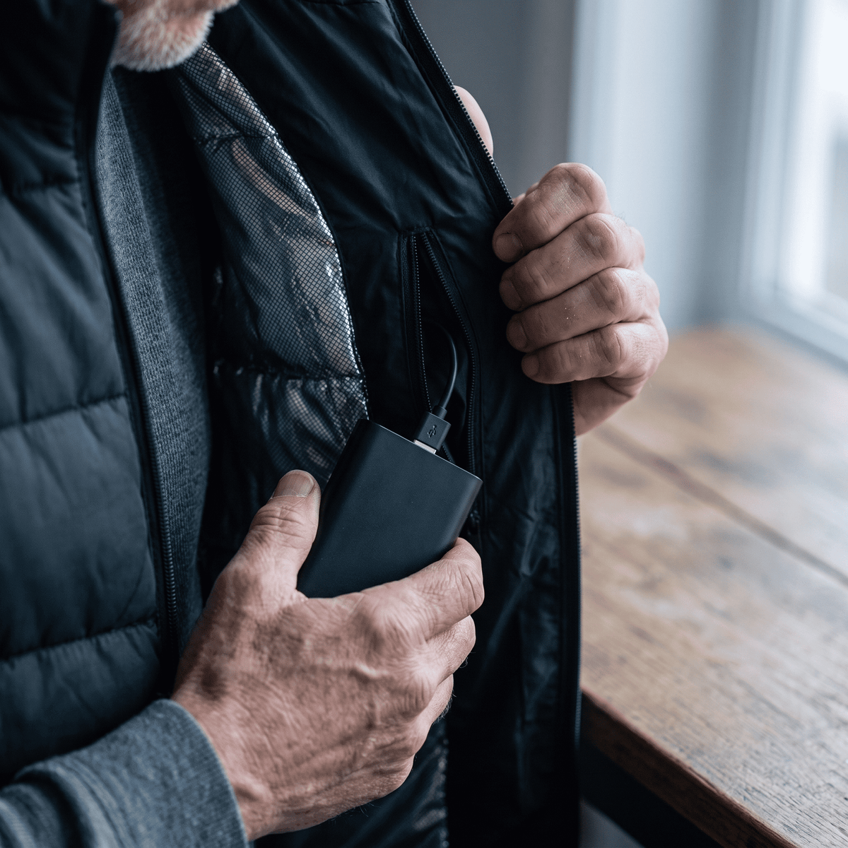Power bank being placed into the heated vest's inner pocket